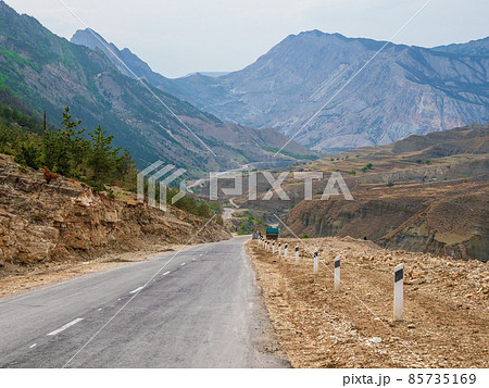 Asphalt road stretching into the distance. Hot asphalt road through the hills and mountains. Turn on an empty mountain road. Old cracked asphalt mountain road in Dagestan. Asphalt road stretching into the distance. Hot asphalt road through the hills and mountains. Turn on an empty mountain road. Old cracked asphalt mountain road in Dagestan. 85735169