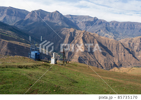 The electricity station is high in the mountains. Poles with wires for electricity in rural mountainous areas. Electricity in the village. Mountains and blue cloudy sky. The electricity station is high in the mountains. Poles with wires for electricity in rural mountainous areas. Electricity in the village. Mountains and blue cloudy sky. 85735170