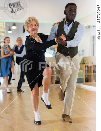 Woman pensioner with african man practising charleston Woman pensioner with african man practising charleston 85736097