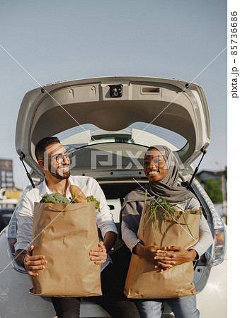 Diverse couple with grocery at car trunk Diverse couple with grocery at car trunk 85736686