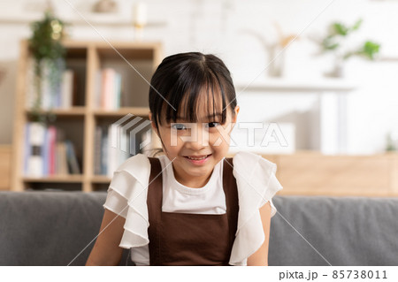 Portrait of asian children smile looking at camera at home.Happiness Little toddler laughing with white teeth on couch in cozy home.Healthy kid concept 85738011