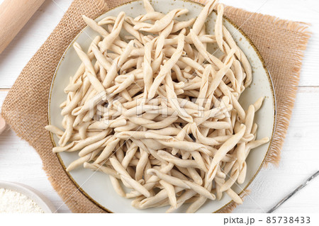 Whole grain wheat raw apulian pasta called Pizzarieddi or maccaruni on a ceramic plate on white wooden table Whole grain wheat raw apulian pasta called Pizzarieddi or maccaruni on a ceramic plate on white wooden table 85738433