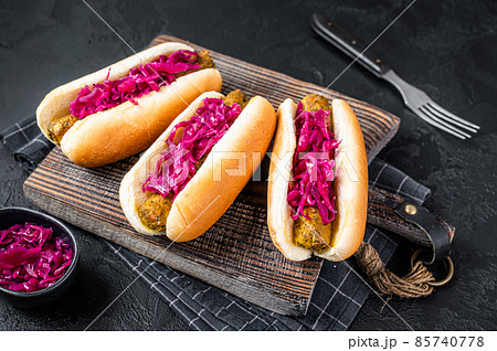 Homemade Vegan hot-dog with meatless Vegetarian sausage and cabbage. Black background. Top view Homemade Vegan hot-dog with meatless Vegetarian sausage and cabbage. Black background. Top view 85740778