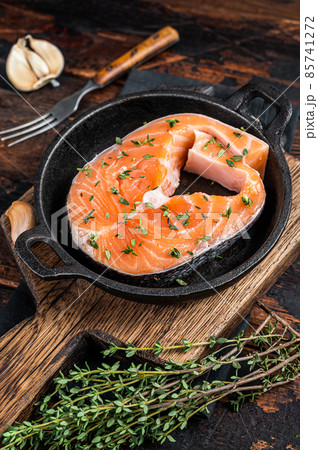 Trout or Salmon raw steaks in a pan with thyme. Dark wooden background. Top view Trout or Salmon raw steaks in a pan with thyme. Dark wooden background. Top view 85741272
