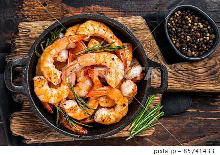 Roast Prawns Shrimps in a pan with herbs and garlic. Dark wooden background. Top view Roast Prawns Shrimps in a pan with herbs and garlic. Dark wooden background. Top view 85741433