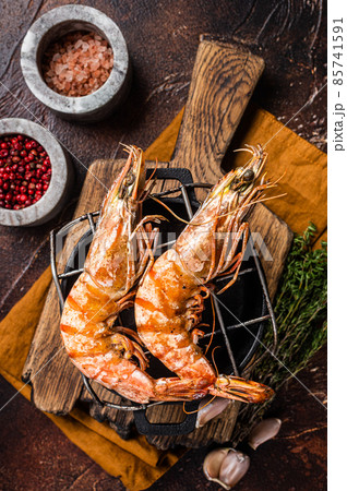 BBQ roasted Giant shrimps Langoustine on grill with herbs. Dark background. Top view BBQ roasted Giant shrimps Langoustine on grill with herbs. Dark background. Top view 85741591