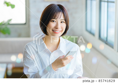 リビングでスマホを操作する笑顔の若い女性 85741629
