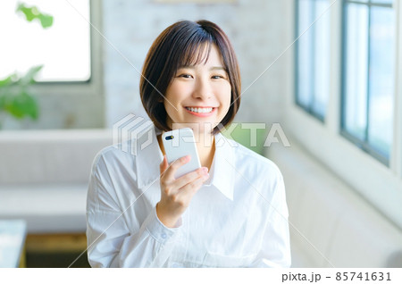 リビングでスマホを操作する笑顔の若い女性 85741631