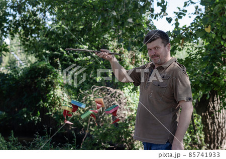 An adult man holds children's ships tied to a branch An adult man holds children's ships tied to a branch 85741933