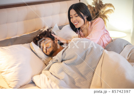 Woman touching mans head with closed eyes in bed Woman touching mans head with closed eyes in bed 85742397