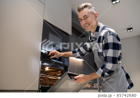Man turning toggle switch of oven looking at camera 85742680