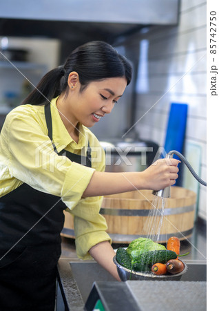 Woman in the kitchen washing vegetables before cooking Woman in the kitchen washing vegetables before cooking 85742750
