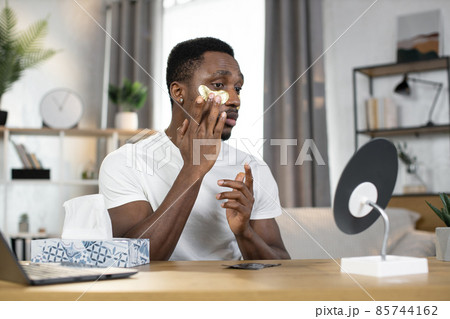 Sporty happy African guy applying golden patches under his eyes 85744162