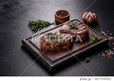 Fresh juicy delicious beef steak on a dark background Fresh juicy delicious beef steak on a dark background 85744401