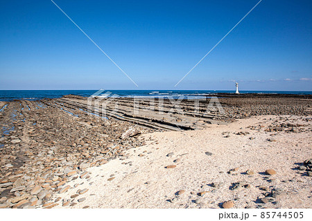 宮崎日向灘の青空に隆起海床できた鬼の洗濯岩の上に海積宮の青島神宮に祀られる海の神様を案内する白い燈台 85744505