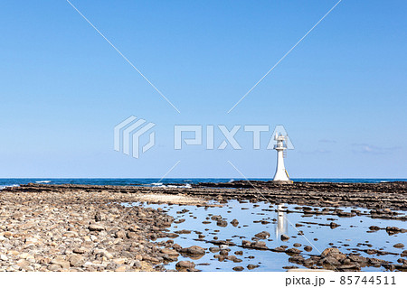 宮崎日向灘の青空に隆起海床できた鬼の洗濯岩の上に海積宮の青島神宮に祀られる海の神様を案内する白い燈台 85744511