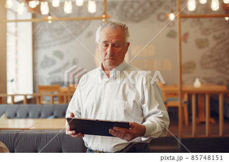 Elegant old man in a cafe using a laptop Elegant old man in a cafe using a laptop 85748151