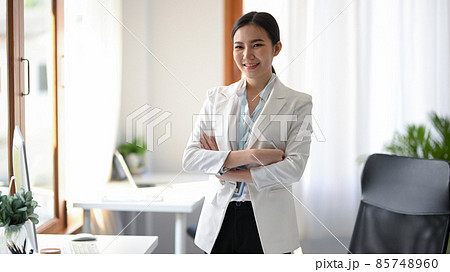 Businesswoman standing with arms crossed or arms folded in the office. 85748960