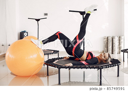 Jumping young woman on a trampoline 85749591