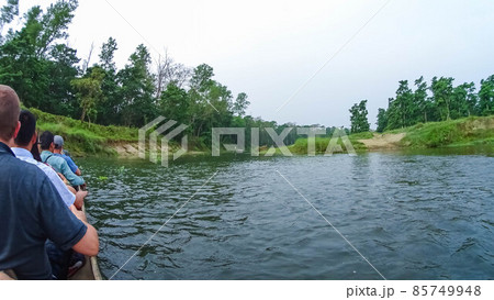 Unidentified people canoeing safari on wooden boats Pirogues on the Rapti river, in Chitwan National Park 85749948