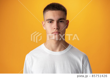 Portrait of a teen boy smiling against yellow background 85751426