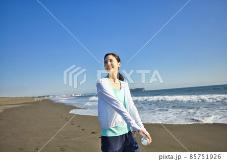 砂浜でウオーキングをするスポーツウエアの若い女性 85751926