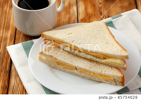 Toast sandwich and cup of coffee on napkin on wooden table 85754029
