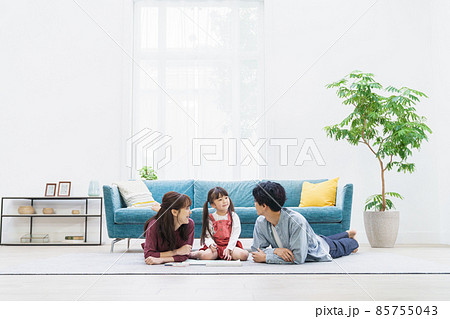 リビングルームで寝そべる3人家族 85755043