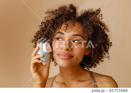Beautiful lady with curly hairstyle posing against beige wall 85755066