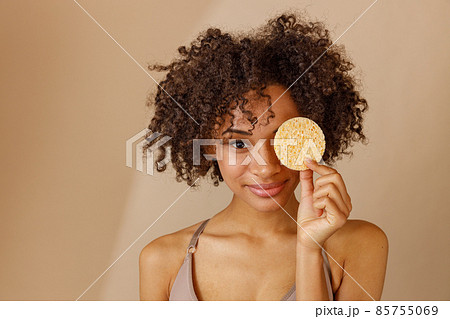 Stylish female model posing against beige wall 85755069
