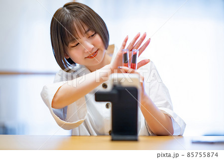 スマートフォンを使ってコスメグッズを紹介する女性 スマートフォンを使ってコスメグッズを紹介する女性 85755874