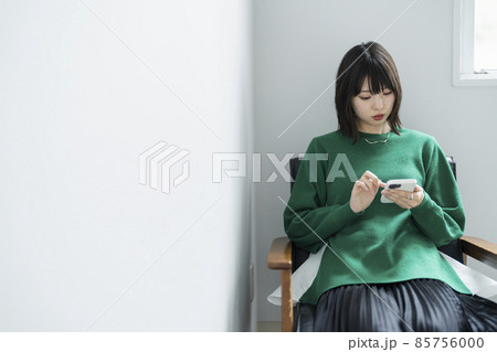 部屋でスマートフォンを使う女性 85756000