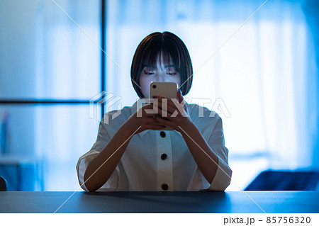 厳しい表情でスマートフォンを見つめる女性 85756320