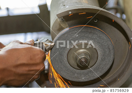 The worker regrinding the drill tool with abrasive wheel. 85756929