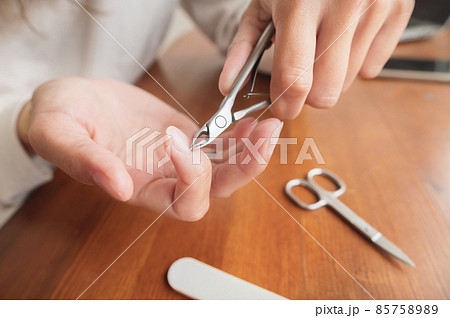 Close-up of hand of caucasian young woman doing manicure at home with nail supplies. Close-up of hand of caucasian young woman doing manicure at home with nail supplies. 85758989