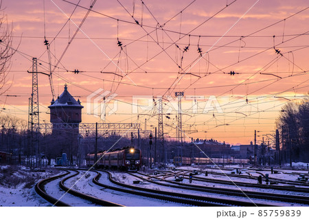 The passenger train travels on the tracks on a cold winter morning in the city. Selective focus 85759839
