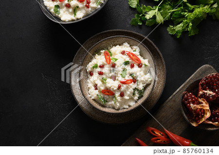 Curd Rice with pomegranate, cilantro, mustard seeds, ginger on a black background. Indian cuisine 85760134