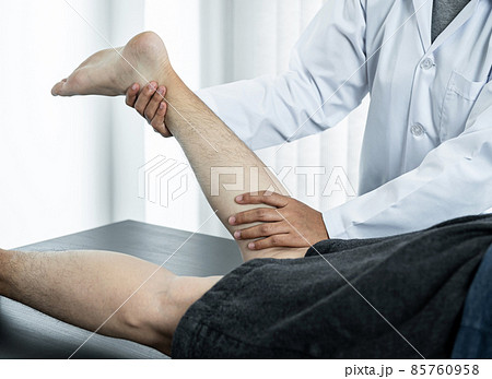 Female physiotherapist doing healing treatment and rehabilitation injured legs and ankle of patient by stretching Female physiotherapist doing healing treatment and rehabilitation injured legs and ankle of patient by stretching 85760958