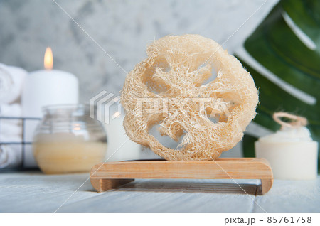 Natural loofah scrubber on podium in bathroom. Zero waste in life. Relaxation spa concept, candles, beauty.. Natural loofah scrubber on podium in bathroom. Zero waste in life. Relaxation spa concept, candles, beauty.. 85761758