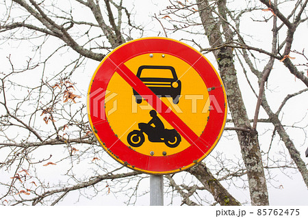 European round traffic sign, the passage of vehicles and motorcycles prohibited. On autumn trees background. European round traffic sign, the passage of vehicles and motorcycles prohibited. On autumn trees background. 85762475