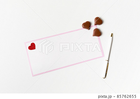Romantic letter, white blank greeting card with a pen and heart-shaped chocolate candies on white 85762655