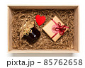 Wooden box with present wrapped in brown craft paper with red ribbon,  jam jar, filled with paper filler 85762658
