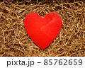 Present box with big red heart lying on brown shredded craft paper filler 85762659