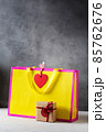 Valentines day present gift bag in bright colors pink and yellow with little wrapped present box 85762676