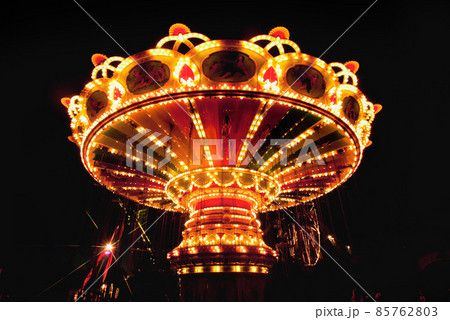 Colorful chain swing carousel in motion at amusement park at night. 85762803