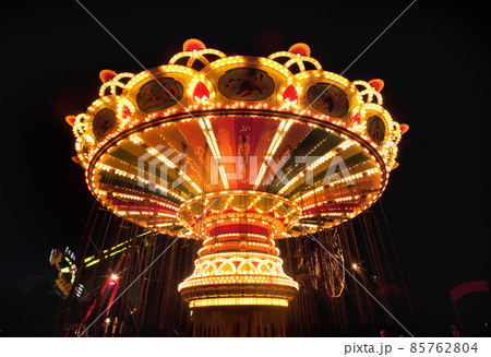 Colorful chain swing carousel in motion at amusement park at night. 85762804