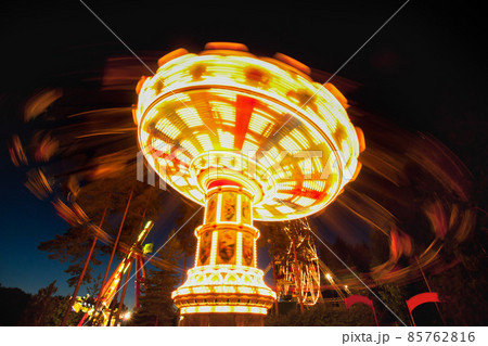 Colorful chain swing carousel in motion at amusement park at night. 85762816