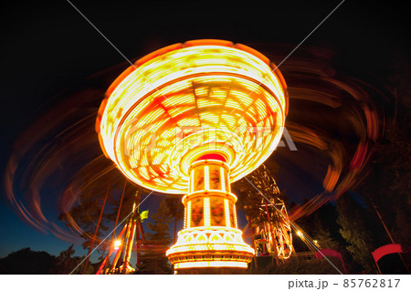 Colorful chain swing carousel in motion at amusement park at night. 85762817