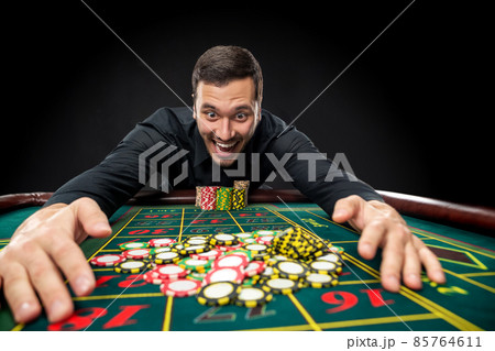 Young handsome man playing roulette wins at the casino Young handsome man playing roulette wins at the casino 85764611