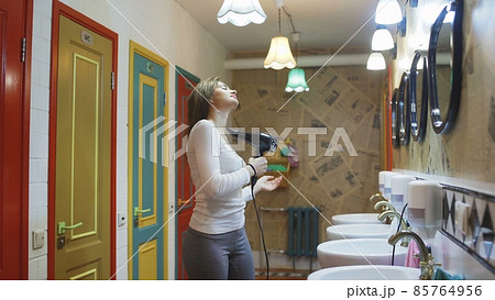 A young woman dries her hair with a hair dryer in a hotel 85764956